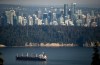 A bulk carrier cargo ship travels into port as a Harbour Air seaplane flies towards Stanley Park and the downtown skyline, in Vancouver, on Wednesday, July 27, 2022. The government of British Columbia will not support an Indigenous-led bid to host the 2030 Olympics in the province. THE CANADIAN PRESS/Darryl Dyck