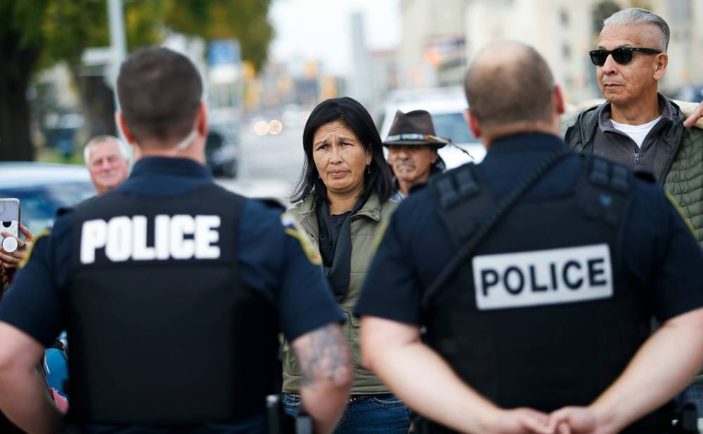 A group of protestors carrying teepee poles were stopped from entering the grounds of the legislature on Monday by police. (John Woods / Winnipeg Free Press)