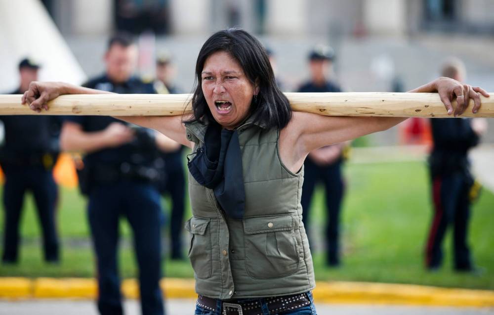 A protestor yells after she was allowed to collect her confiscated pole on Monday after being stopped from entering the legislative grounds by police. (John Woods / Winnipeg Free Press)