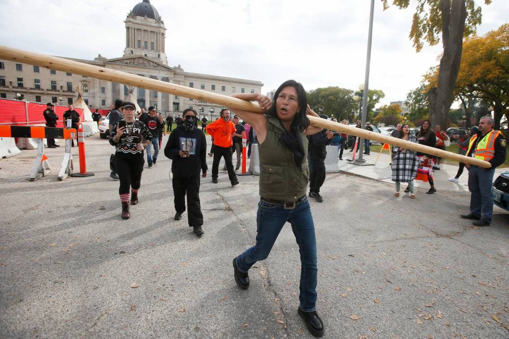 A protestor yells and walks away after she was allowed to collect her confiscated pole. (John Woods / Winnipeg Free Press)