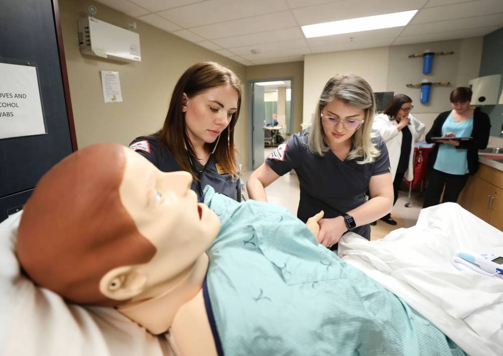 Red River College Polytechnic second-year nursing students Melissa Ciurko (left) and Jenna Forsyth assess a high-fidelity simulated mannequin in their department on Tuesday. (Ruth Bonneville / Winnipeg Free Press)