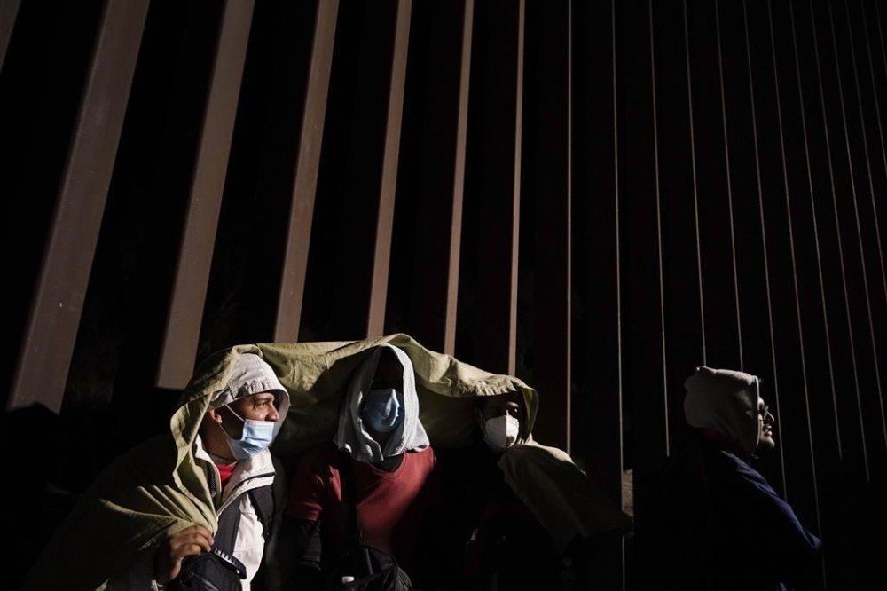FILE - Four men from Cuba try to keep warm after crossing the border from Mexico and surrendering to authorities to apply for asylum on Nov. 3, 2022, near Yuma, Ariz. U.S. District Judge Emmet Sullivan on Tuesday, Nov. 15, ordered the Biden administration to lift Trump-era asylum restrictions that have been a cornerstone of border enforcement since the beginning of COVID-19. Sullivan ruled that Title 42 authority end immediately for families and single adults, saying it violates federal rule-making procedures. (AP Photo/Gregory Bull, File)