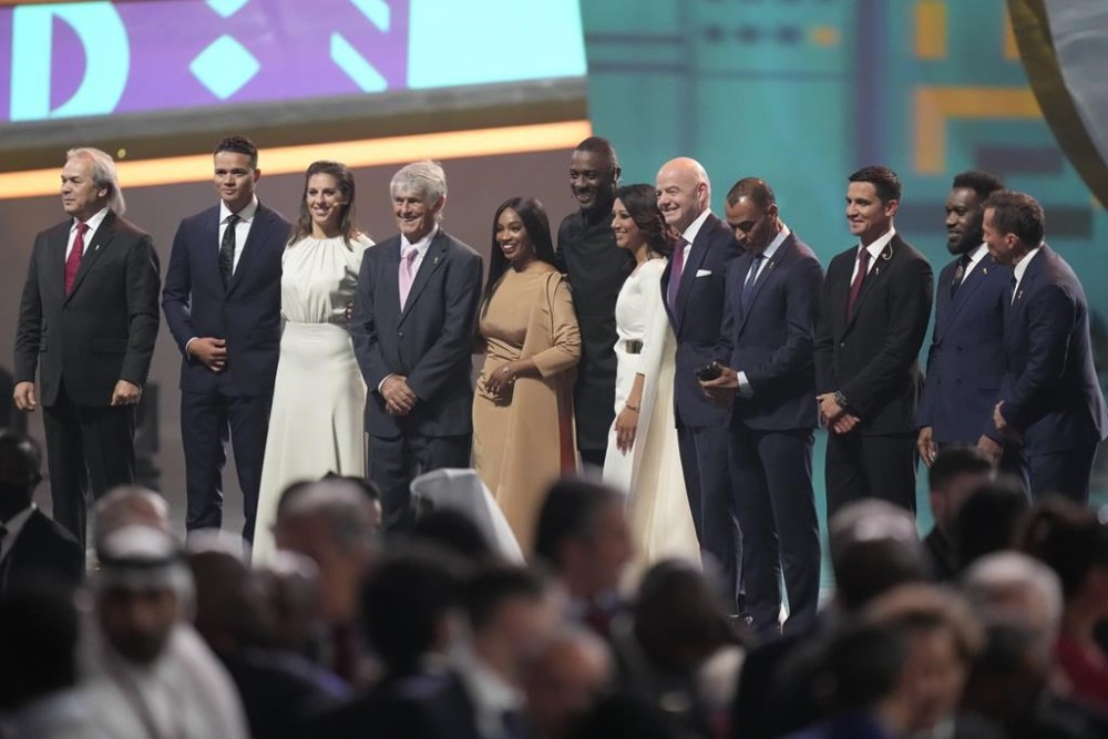 Rabah Madjer, Jermaine Jenas, Carli Lloyd, Bora Milutinovic, Samantha Johnson, Idris Elba, Reshmin Chowdhury, Gianni Infantino, FIFA President, Cafu, Tim Cahill, Jay-Jay Okocha and Lothar Matthaus, from left, pose for a photograph after the 2022 soccer World Cup draw at the Doha Exhibition and Convention Center in Doha, Qatar, Friday, April 1, 2022. (AP Photo/Darko Bandic, File)