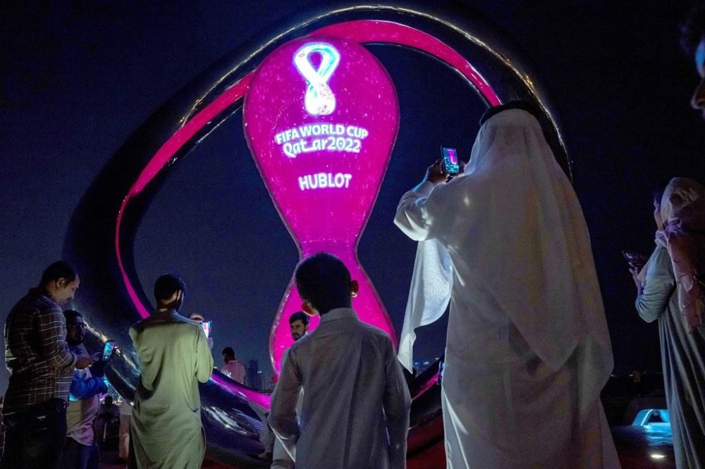 People take photos with the official FIFA World Cup Countdown Clock on Doha's corniche, in Qatar, Friday, Oct. 14, 2022. Carrie Serwetnyk, the first woman inducted into the Canadian Soccer Hall of Fame, is in Qatar for the 2022 World Cup and says the tournament is