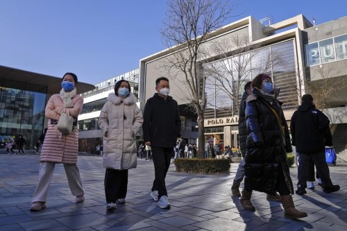 People wearing face masks walk through a reopened open air shopping mall in Beijing, Sunday, Dec. 4, 2022. China on Sunday reported two additional deaths from COVID-19 as some cities move cautiously to ease anti-pandemic restrictions amid increasingly vocal public frustration over the measures. (AP Photo/Andy Wong)
