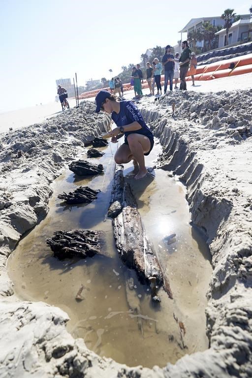 Arielle Cathers jots down information in a notebook at the site of an exposed wooded structure in the sand on Tuesday in Daytona Beach Shores, Fla. (John Raoux / The Associated Press)