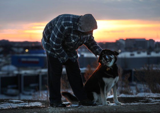 Jarette Senek plays with his dog Dakari, a husky cross, at Westview Park dog park as the sun sets Thursday. (Ruth Bonneville / Winnipeg Free Press)