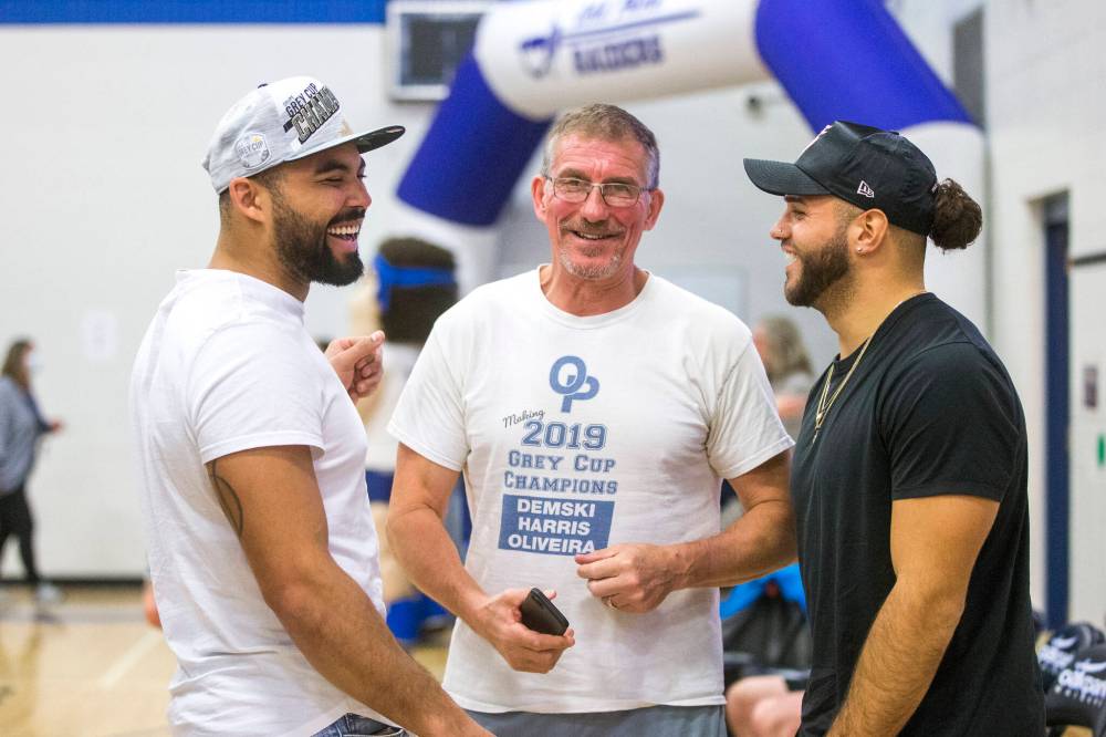 Stu Nixon (centre) greets Nic Demski (left) and Brady Olivera during their visit to Oak Park School with the Grey Cup in May. (Mikaela MacKenzie / Winnipeg Free Press files)