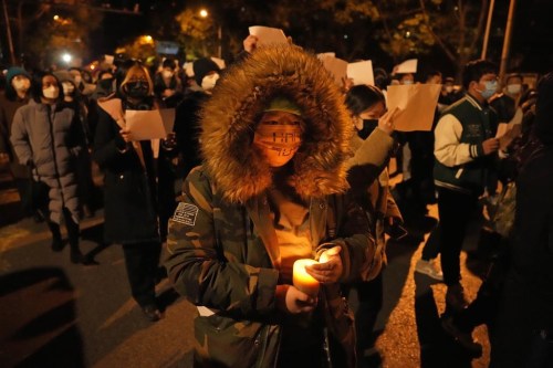 File - Protesters hold up blank papers and chant slogans as they march in protest against strict anti-virus measures in Beijing, Sunday, Nov. 27, 2022. Police in the southern Chinese city of Guangzhou have detained at least four people for more than a week after they attended nationwide protests against COVID-19 restrictions in late November, according to activists, family members and friends of the detained. (AP Photo/Ng Han Guan, File)