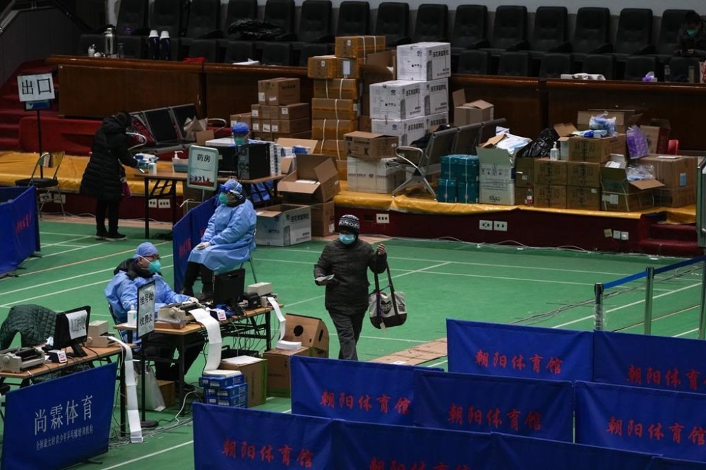 Medical workers tend to residents at a gymnasium converted into a fever clinic in Beijing, Sunday, Dec. 18, 2022. Deaths linked to the coronavirus are appearing in Beijing after weeks of China reporting no fatalities, even as the country is seeing a surge of cases. (AP Photo/Andy Wong)