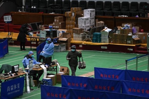 Medical workers tend to residents at a gymnasium converted into a fever clinic in Beijing, Sunday, Dec. 18, 2022. Deaths linked to the coronavirus are appearing in Beijing after weeks of China reporting no fatalities, even as the country is seeing a surge of cases. (AP Photo/Andy Wong)