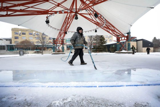 Justin Prescott slowly releases a thin layer of water while flooding the ice under The Forks canopy. (Ruth Bonneville / Winnipeg Free Press)