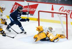 Winnipeg Jets’ Adam Lowry (17) celebrates as Kyle Connorís (not shown) shot sneaks through the pads of Nashville Predators goaltender Juuse Saros (74) for the winning goal in NHL overtime action in Winnipeg, Thursday, December 15, 2022. THE CANADIAN PRESS/John Woods