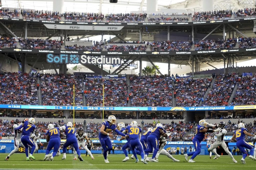Los Angeles Chargers quarterback Justin Herbert (10) hands the ball to running back Austin Ekeler (30) during the first half of an NFL football game against the Denver Broncos Sunday, Dec. 10, 2023, in Inglewood, Calif. (AP Photo/Marcio Jose Sanchez)
