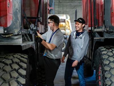 Airfield maintenance specialists enjoying working together while carefully coordinating their duties to prepare snow clearing equipment at Winnipeg Airports Authority.