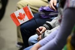 A young new Canadian holds a flag as she takes part in a citizenship ceremony in Ottawa. (Sean Kilpatrick / The Canadian Press files)