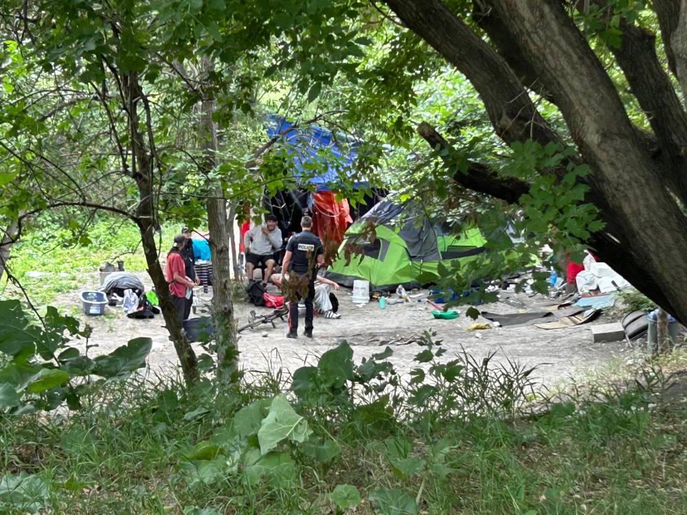 TYLER SEARLE / FREE PRESS
Police speak with people in an encampment on the riverbank, near the southern edge of St. John’s Park.