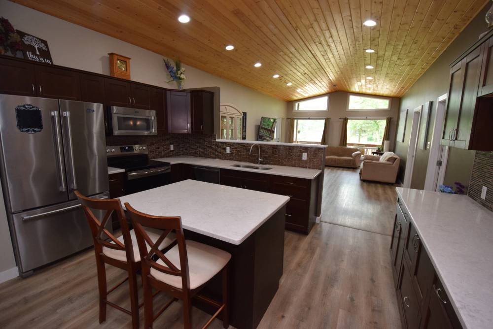 The kitchen offers modern function and style with a compact island, quartz countertops, maple cabinets and stainless appliances.