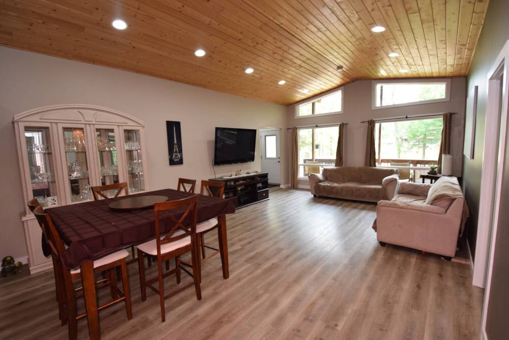 A living room/dining room with pine vaulted ceiling and front wall of windows is a beautiful, bright space.