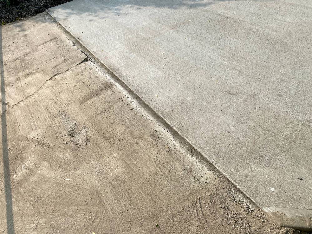 The new concrete pad (right) was finished an inch higher than the old concrete driveway approach to allow for a clean seam once the new asphalt is added.