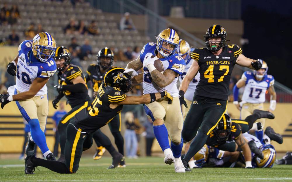 PETER POWER / THE CANADIAN PRESS
Winnipeg Blue Bombers running back Brady Oliveira (20) gains some yards on the ground before being tackled by Hamilton Tiger Cats defensive back Destin Talbert (25) during first half CFL football game action in Hamilton, Ont. on Friday, September 12, 2025.