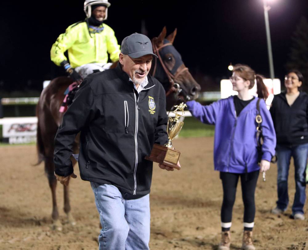 JASON HALSTEAD PHOTO / ASSINIBOIA DOWNS
Five-time leading Assiniboia Downs trainer Jerry Gourneau walks into the winner’s circle with the Gold Cup trophy on Tuesday after winning the prestigious race with Mr Jaws for seven-time leading owner Henry S. Witt Jr.