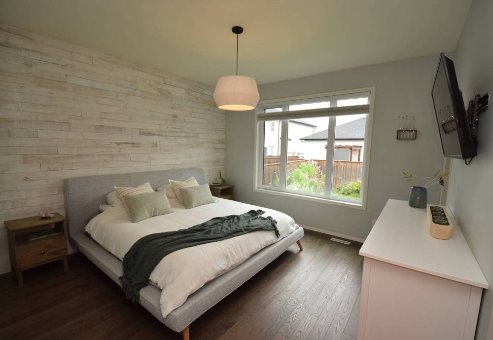 TODD LEWYS / FREE PRESS
A large window lets in plenty of light in the primary bedroom, while engineered hardwoods and a barn wood feature wall behind the bed add warmth and texture.