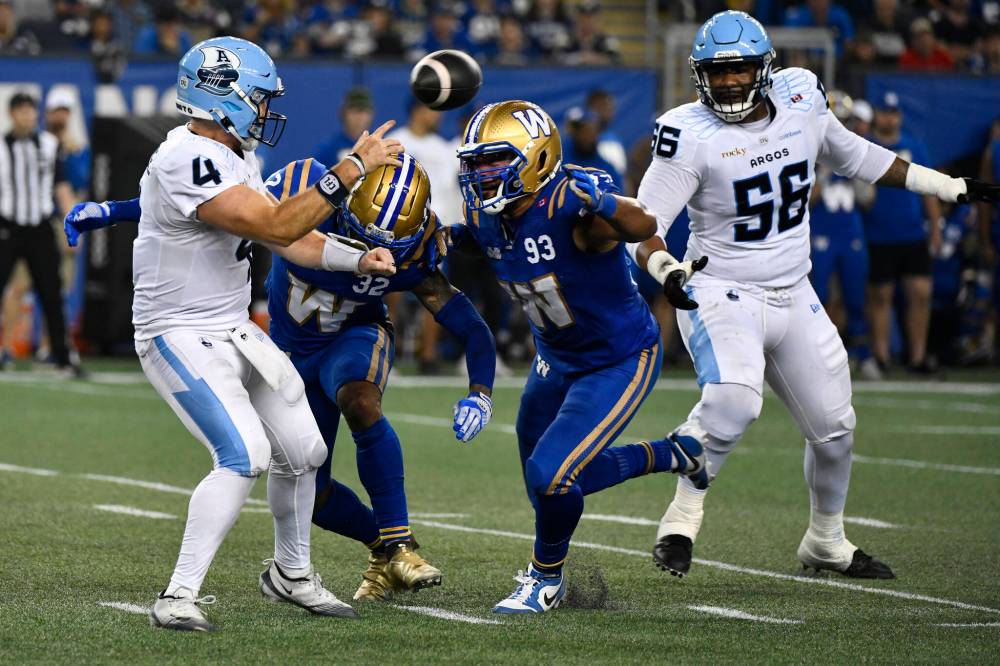 FRED GREENSLADE / THE CANADIAN PRESS FILES
Bombers’ DE James Vaughters (centre) puts pressure on the Argos QB Nick Arbuckle.