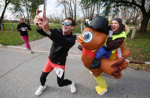 JOHN WOODS / FREE PRESS
                                At the turning point of Monday’s Turkey Trot five-kilometre race, a runner takes a selfie with volunteer Dana, who is wearing a festive turkey suit.