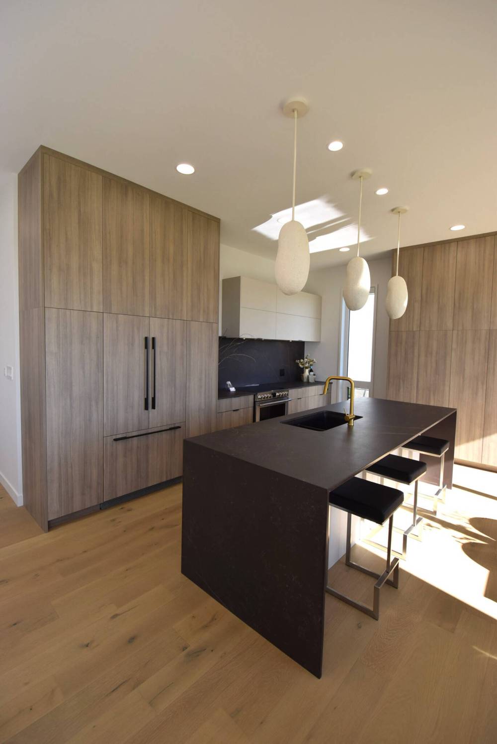 Todd Lewys / Free Press
A nine-foot island with matte-black porcelain countertop, waterfall sides and warm woodgrain-style cabinetry serves as the anchor point of the elegantly understated kitchen in Artista Homes’ spacious bungalow in Forest Grove Estates.