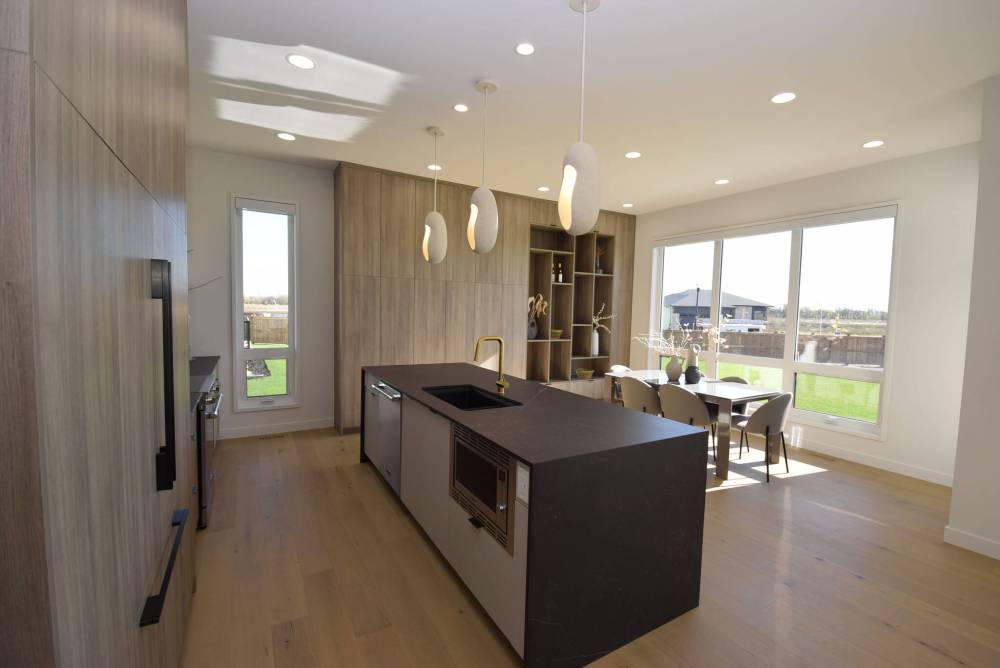 Todd Lewys / Free Press
A nine-foot island with matte-black porcelain countertop, waterfall sides and warm woodgrain-style cabinetry serves as the anchor point of the elegantly understated kitchen in Artista Homes’ spacious bungalow in Forest Grove Estates.