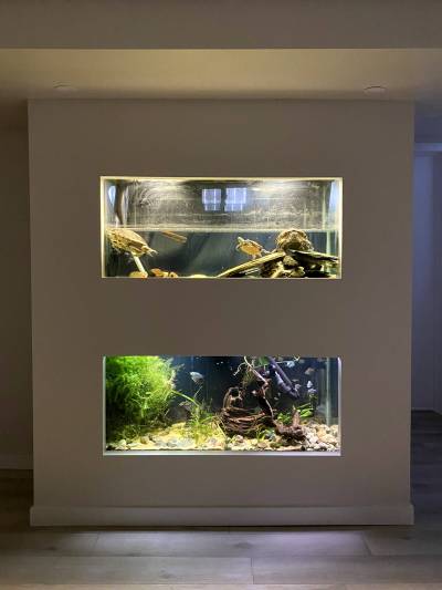 A built-out wall features two large stacked aquariums for the homeowners&rsquo; pet turtles and fish.