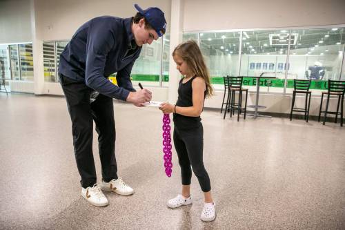 BROOK JONES / FREE PRESS
                                Manitoba Moose defenceman Garrett Brown (left) signs an autograph for six-year-old Braelyn Julius at Hockey For All Centre on Thursday.