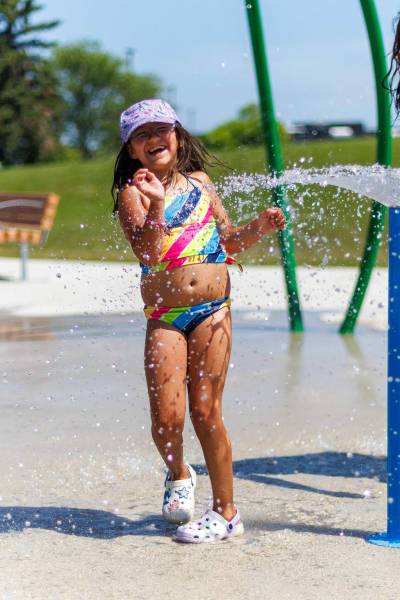 MIKE DEAL / FREE PRESS Auryanna, 6, along with her mother, Kristen Sanderson (not pictured), take advantage of the cool water at the Maples Spray Pad Monday afternoon. Reporter: Tiago Resko 260713 - Monday, July 13, 2026.