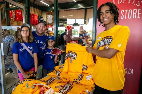 BROOK JONES / FREE PRESS
                                The Winnipeg Goldeyes take on a pesky and all-too-familiar alternate identity, the Manitoba Mosquitoes, for the team&rsquo;s home game against the visiting Lincoln Saltdogs on Friday. Kataali Stoller (right) shows off the special edition merchandise to Cory Ruppanthal and his children, Ava and Owen.