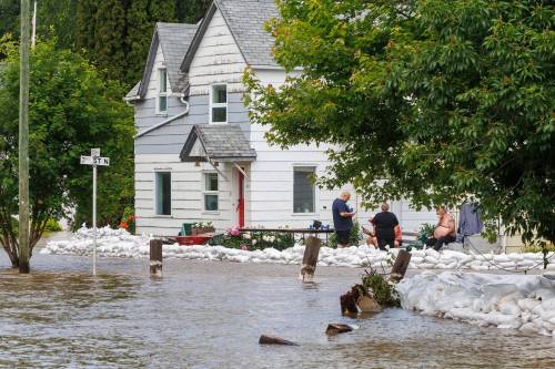 Mike Deal / Free Press files
                                People take a break from sandbagging to protect properties in a flooded area of Swan River on July 2.