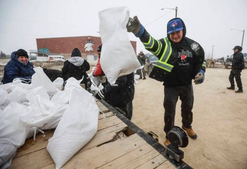 (John Woods / The Canadian Press files) Manitoba Premier Wab Kinew loads sandbags onto a trailer at Peguis First Nation, in April.