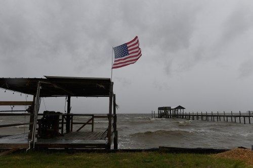 An American flag flaps in the wind generated by the effects of Isaias on an empty beach on Friday, Oct. 9, loom overhead on Friday, Oct. 9, 2026, in Mon Louis Island, Ala. (AP Photo/Octavio Jones)
